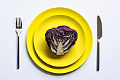From above of halved red cabbage placed on yellow plates on white background