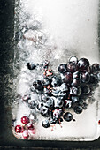 Top view of piece of ice with grapes placed on metal tray at sunlight