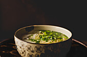 Chinese ramen meal in ceramic bowl with oriental ornament placed on wooden table on black background