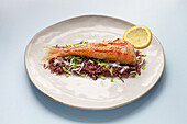 Köstlicher Rotbarbenfisch und verschiedene Reissorten, serviert auf einem Teller mit einer Zitronenscheibe auf einem Tisch im Restaurant