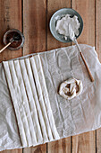 Von oben: rohe Brezel und Teigrollen auf Papier neben Feigenmarmelade und Frischkäse auf einem Holzstapel
