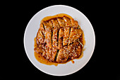 Top view of prepared tasty spicy chicken on white plate on dark table in Asian restaurant