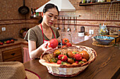 Focused ethnic housewife selecting fresh tomatoes on kitchen while cooking food at home