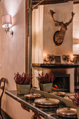 Innenansicht eines Speisesaals mit Tellern und Calluna-Blumen auf einem Regal in der Nähe des Spiegels am Abend