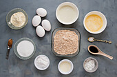 Top view of various ingredients for healthy keto coffee muffins with flour and egg placed on gray background with sweetener