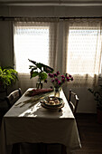 Blick von oben auf einen Tisch mit Knoblauch in einer Schüssel in der Nähe von Getreidegras und einem Glas mit blühenden Blumen in einem ländlichen Haus