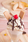 Appetizing sweet milkshake decorated with whipped cream and waffles and cherry on top