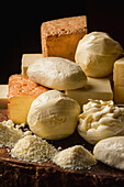 Sammlung italienischer Käsesorten im Ganzen und gerieben auf einem Holztisch