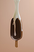 Side view of a chocolate ice cream suspended in the air while bathed in milk from above