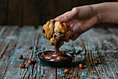 Unbekannte Person taucht mit der Hand einen Muffin in Schokoladencreme