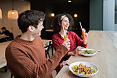 Cheerful multiethnic couple eating healthy breakfast in restaurant