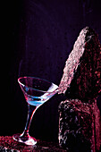 Glas mit alkoholischem Cocktail "Blaue Lagune" auf rauem Stein in hellem Studio