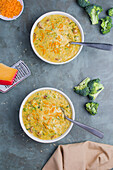 Draufsicht auf Schalen mit leckerer Suppe mit Brokkoli und Käse auf grauem Tisch im Restaurant