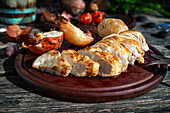 Leckere gegrillte Hühnerbrust auf Teller mit frischen gerösteten Kirschtomaten und Zucchini auf Holztisch mit Zwiebel