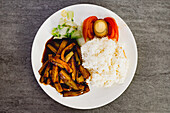 Von oben appetitlich gekochte Yuxiang-Aubergine mit gesundem Gemüse und Reis auf weißem Teller in asiatischem Restaurant