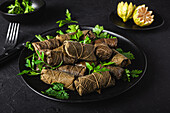 Palatable sarma with parsley lemon and fork and knife on dark background