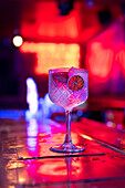 Gut durchdachter Gin-Tonic-Cocktail, dekoriert mit Erdbeeren und trockener Zitronenscheibe in einer Bar