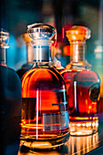 Transparente Glasflaschen mit Whiskey auf dem Tresen einer dunklen Bar bei Nacht