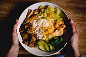 Von oben betrachtet hält eine Frau ein leckeres taiwanesisches Bento auf einem Holztisch in einem asiatischen Cafe