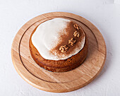 Top view of tasty carrot cake with walnuts and cinnamon powder on icing sugar glaze on light background