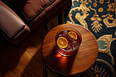 Blick von oben auf ein Cocktailglas auf einem Holztisch neben einem braunen Sofa. Generative KI
