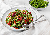 Von oben köstlicher Salat mit Rucola und Quitten, serviert auf einem Teller mit Soße auf dem Tisch