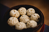 Hot delicious steamed xiaolongbao in bamboo basket on table in Asian restaurant kitchen
