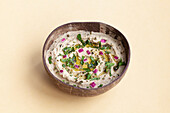 From above of appetizing traditional Baba ghanoush dish made of eggplants and garnished with herbs served in bowl on beige background