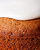 Close - up of tasty carrot cake piece on icing sugar glaze on light background