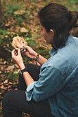 Von oben abgeschnittene unerkennbare Mykologin, die im Wald Schmutz von einem Ramaria-Pilz entfernt