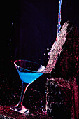 Glass of Blue Lagoon alcoholic cocktail placed on rough stone in bright studio