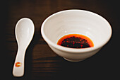 Bowl of spicy chili sauce on wooden table