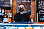 bartender near wine bottle on counter in restaurant with many signboards