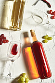 Arrangement feiner Rot- und Weißweine auf rissiger Oberfläche inmitten von Weingläsern und Trauben