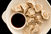 From above composition of steamed and roasted dumplings on white ceramic plate with soy sauce