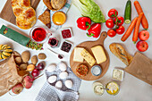 Draufsicht auf verschiedene gesunde Lebensmittel auf Brettern und Handtüchern auf einem weißen Tisch