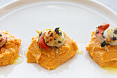 Von oben leckere Jakobsmuscheln mit köstlichem Süßkartoffelpüree auf weißem Teller auf dem Tisch serviert