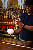 Bartender working with shaker for mixing a cocktail in the bar