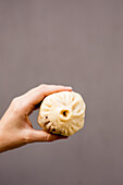 Unrecognizable female showing yummy Sheng Jian Bao to camera