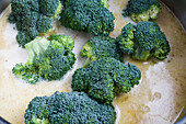 Frischer grüner Brokkoli kocht in Käsesuppe in einem Stahltopf von oben