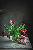 Glass vase with red tulips on the table by the window