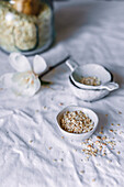 A serene setup featuring homemade rolled oats in a white ceramic bowl against a light textured background, accompanied by a glass jar and a hint of floral decoration