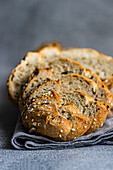 Close up view of freshly sliced sourdough bread with seeds on a textured gray cloth background