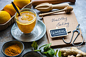 A healthy turmeric lemon drink amidst fresh ingredients and Healthy Eating notebook on a textured surface