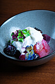 Creamy Stracciatella cheese atop a vibrant beetroot and berry salad, garnished with edible flowers.