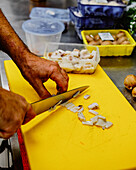 Anonymous chef is slicing mushrooms on a vibrant yellow cutting board, with kitchen containers in the background