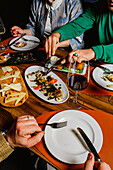 Eine Gruppe von Freunden versammelt sich um einen mit köstlichen Gerichten gedeckten Tisch und teilt eine Mahlzeit in einer gemütlichen, intimen Umgebung
