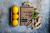 A notebook labeled Healthy Eating with lemons, ginger, and a stethoscope on a stone background