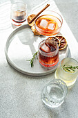 Eine Reihe von alkoholischen Getränken in einzigartigen Gläsern, garniert mit Kräutern und Zitrusfrüchten, präsentiert auf einem runden Tablett bei natürlichem Licht