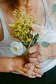 Close-up of elderly hands holding a small bouquet with a gentle touch
